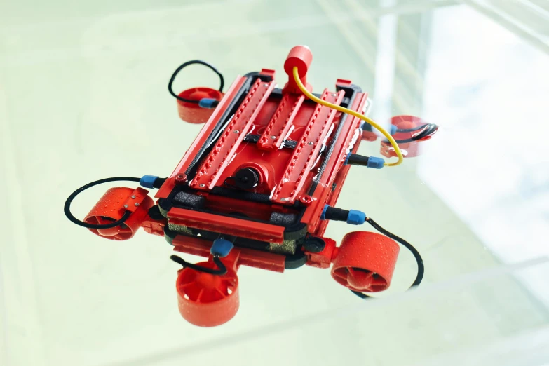 a red robot sitting on top of a glass table, aquatic devices, looking down from above, assembled, from the front