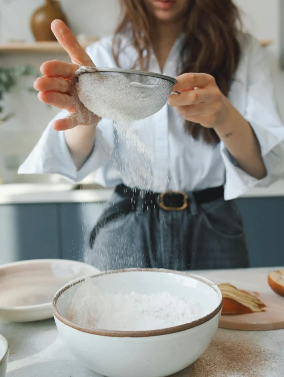 a woman is sprinkling flour into a bowl, inspired by Yukimasa Ida, trending on unsplash, portrait image, gif, full frame image