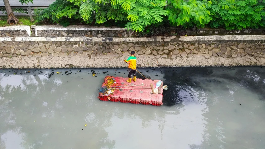 a person on a boat in a body of water, by Julia Pishtar, pexels contest winner, environmental art, blocked drains, jamaica, black and yellow and red scheme, people at work