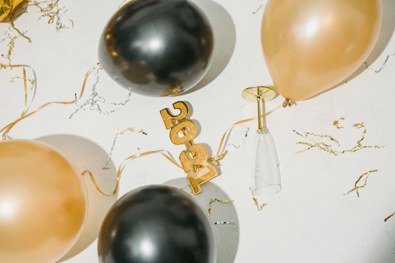 a bunch of balloons sitting on top of a table, by Julia Pishtar, trending on pexels, happening, gold and black, countdown, charcoal and champagne, miniature product photo