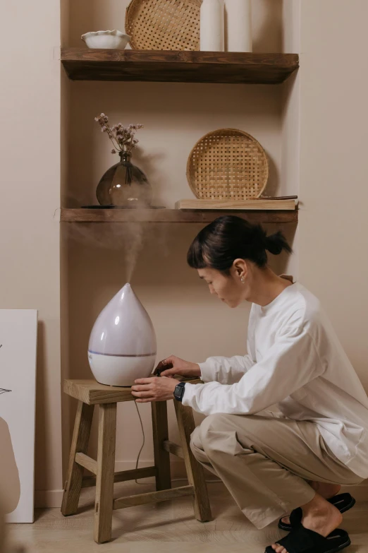 a woman sitting on a stool in front of a humider, trending on pexels, misting, japanese collection product, inspect in inventory image, earthy