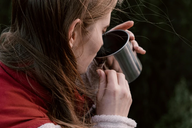 a close up of a person holding a cup, trending on pexels, action shot girl in parka, silver small small small glasses, profile view, picnic