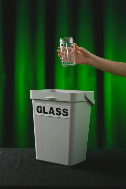 a person holding a glass in front of a trash can, large glasses, glassware, bottle, clear