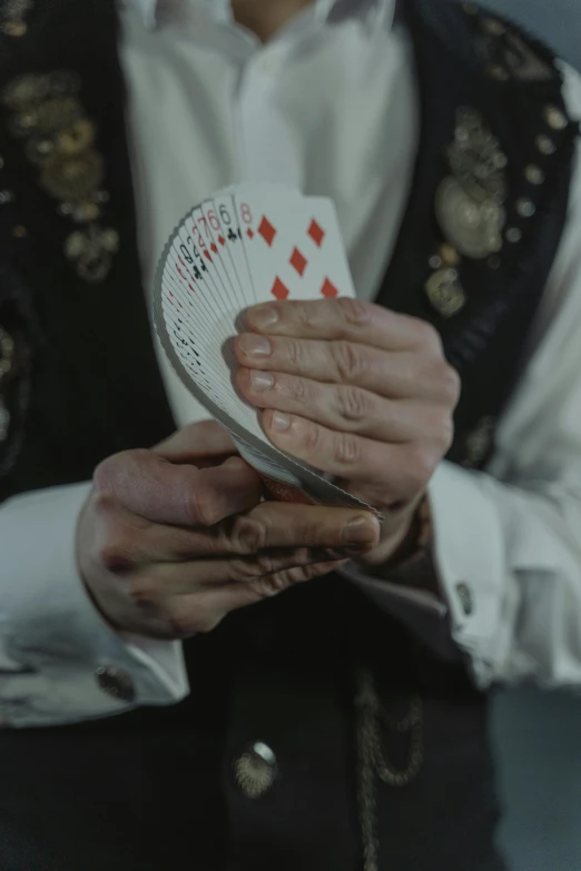 a man in a vest holding a deck of cards, an album cover, by Adam Marczyński, pexels contest winner, renaissance, victorian vampire, single pair of hands, ( ( theatrical ) ), female magician