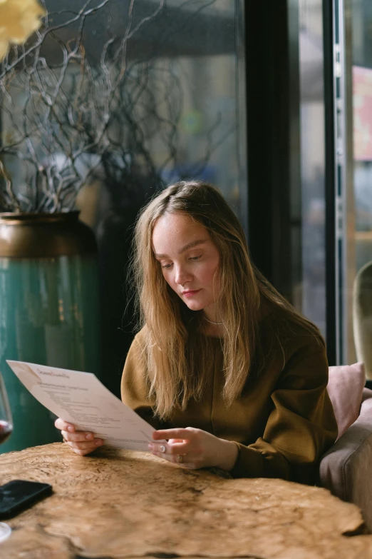 a woman sitting at a table reading a paper, pexels contest winner, renaissance, sydney sweeney, girl with brown hair, post graduate, gif