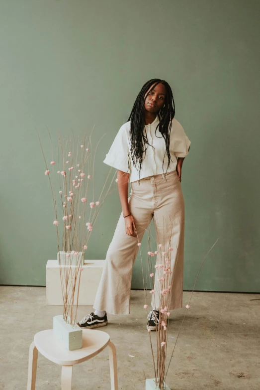 a woman standing in front of a green wall, an album cover, by Dulah Marie Evans, visual art, wearing cargo pants, on a white table, boho neutral colors, sza