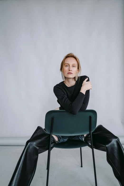 a woman sitting on top of a green chair, a portrait, by Ulrika Pasch, trending on unsplash, helmut lang, eleanor tomlinson, low quality photo, wearing a black sweater