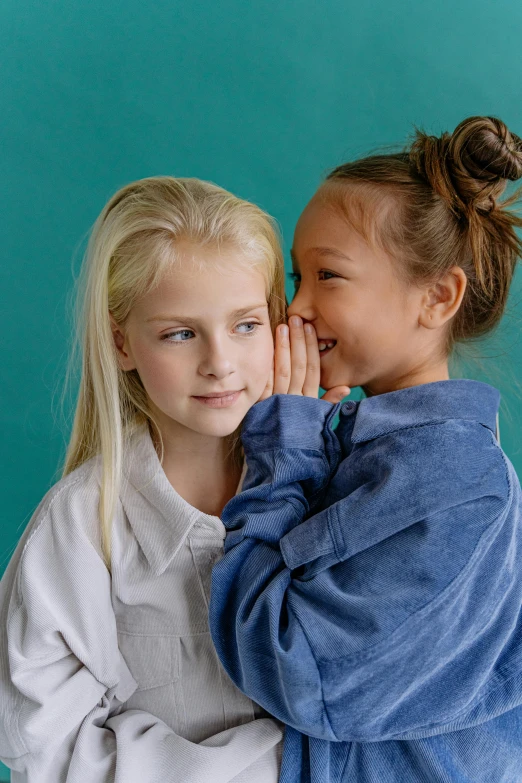 a couple of young girls standing next to each other, trending on unsplash, hand on his cheek, wearing a blue robe, long swept back blond hair, little kid