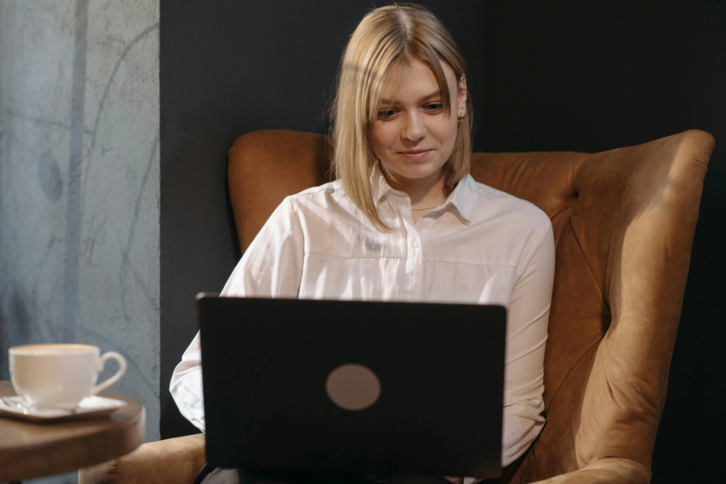 a woman sitting in a chair with a laptop, a portrait, trending on pexels, brown, wearing a white blouse, a girl with blonde hair, thumbnail