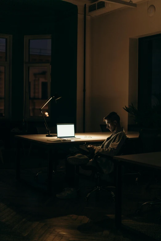 a man sitting at a desk in front of a laptop computer, inspired by Elsa Bleda, unsplash contest winner, an empty backroom at night, ignant, in a classroom, a lonely woman