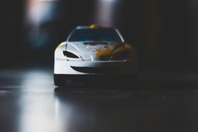 a toy car sitting on top of a table, a tilt shift photo, pexels contest winner, photorealism, full view of a sport car, obscured underexposed view, front profile shot, 🦑 design