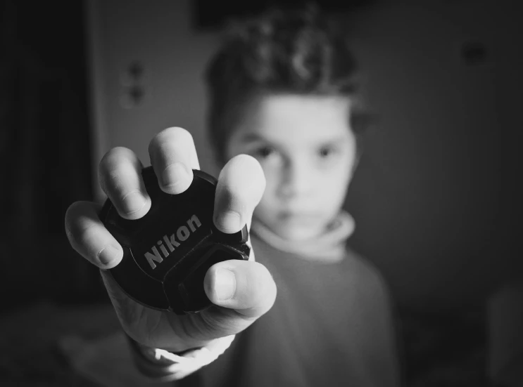 a person holding a remote control in their hand, a black and white photo, by Mirko Rački, kid, nikon camera, looking at camera!!!, medium format