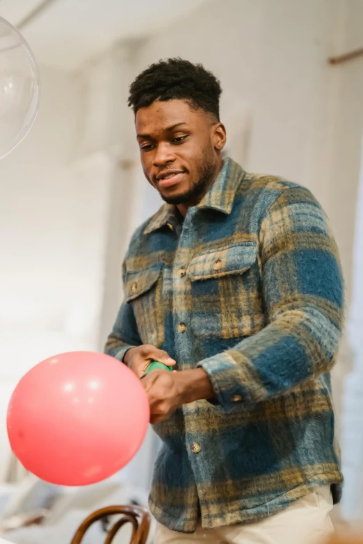 a man holding a pink balloon in a room, jaylen brown, performing, adebanji alade, aged 2 5