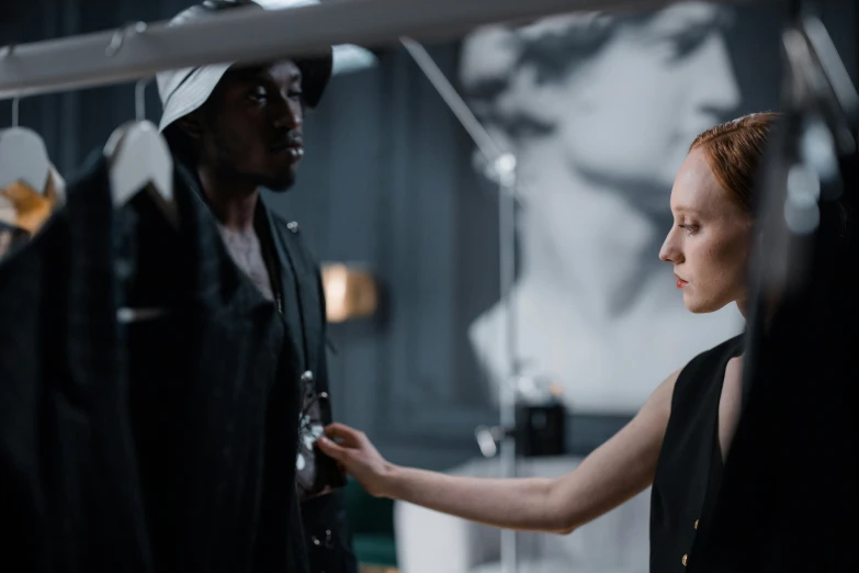 a woman standing next to a man in a room, pexels contest winner, realism, karen gillan, part robot and part black human, behind the scenes photo, black haute couture