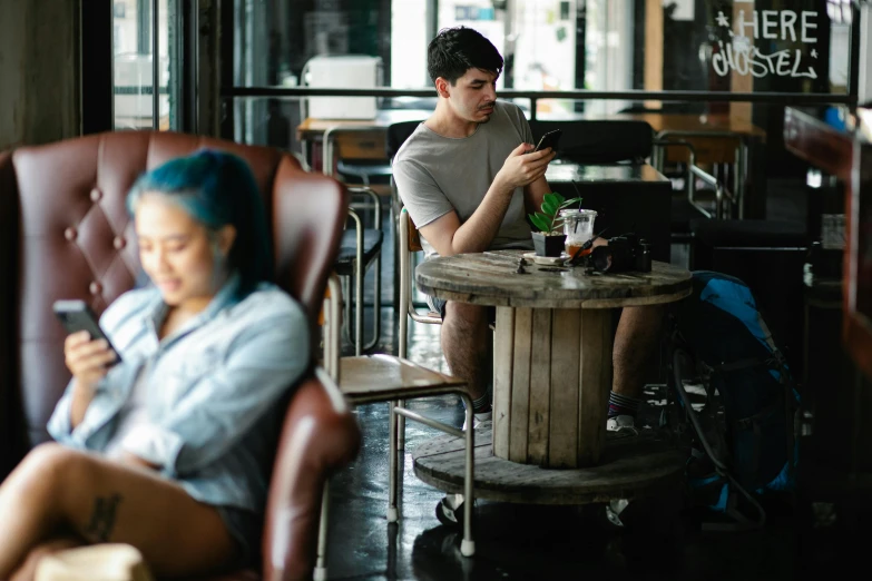 a woman sitting in a chair next to a man on a cell phone, trending on pexels, aussie baristas, people sitting at tables, thumbnail, asher duran