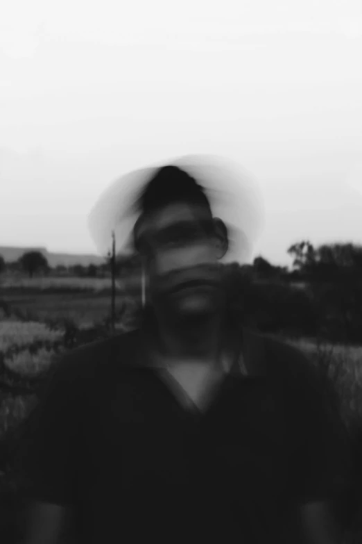 a black and white photo of a man standing in a field, a black and white photo, by Caro Niederer, blurred face, village, blurry and glitchy, josh grover