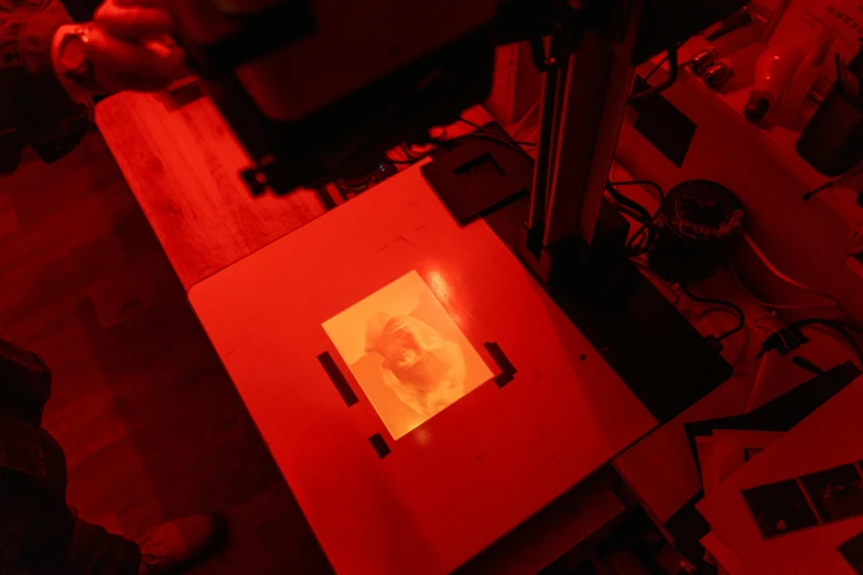 a red box sitting on top of a wooden floor, a hologram, by Daniel Lieske, unsplash, holography, face illuminated, plotter, computer made out of human flesh, printmaking