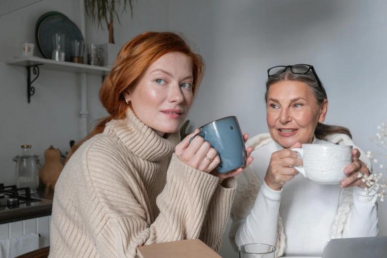 two women sitting at a table with cups of coffee, a portrait, pexels contest winner, ( redhead, going gray, avatar image, family photo