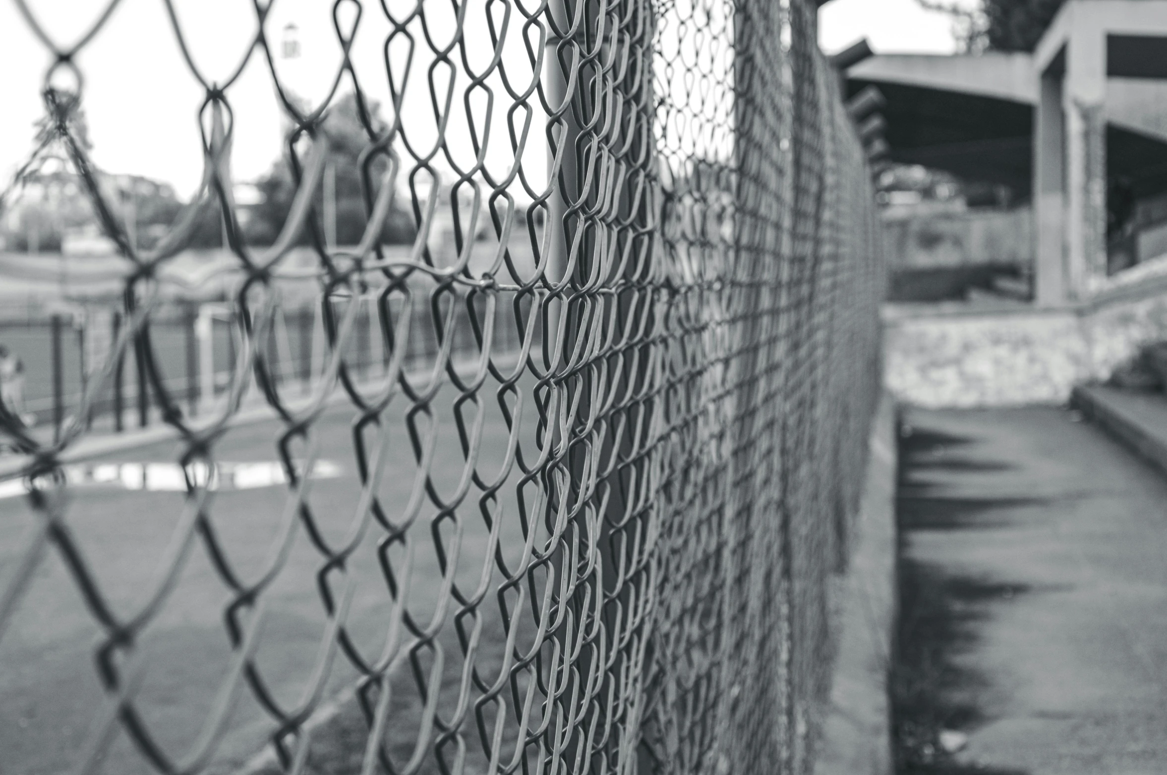 a black and white photo of a chain link fence, a black and white photo, pexels, at a skate park, cages, instagram post, desaturated