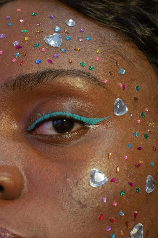 a close up of a woman with glitter on her face, an album cover, trending on pexels, afrofuturism, teal eyebrows, embedded with gemstones, multi colored, dreamy aesthetic