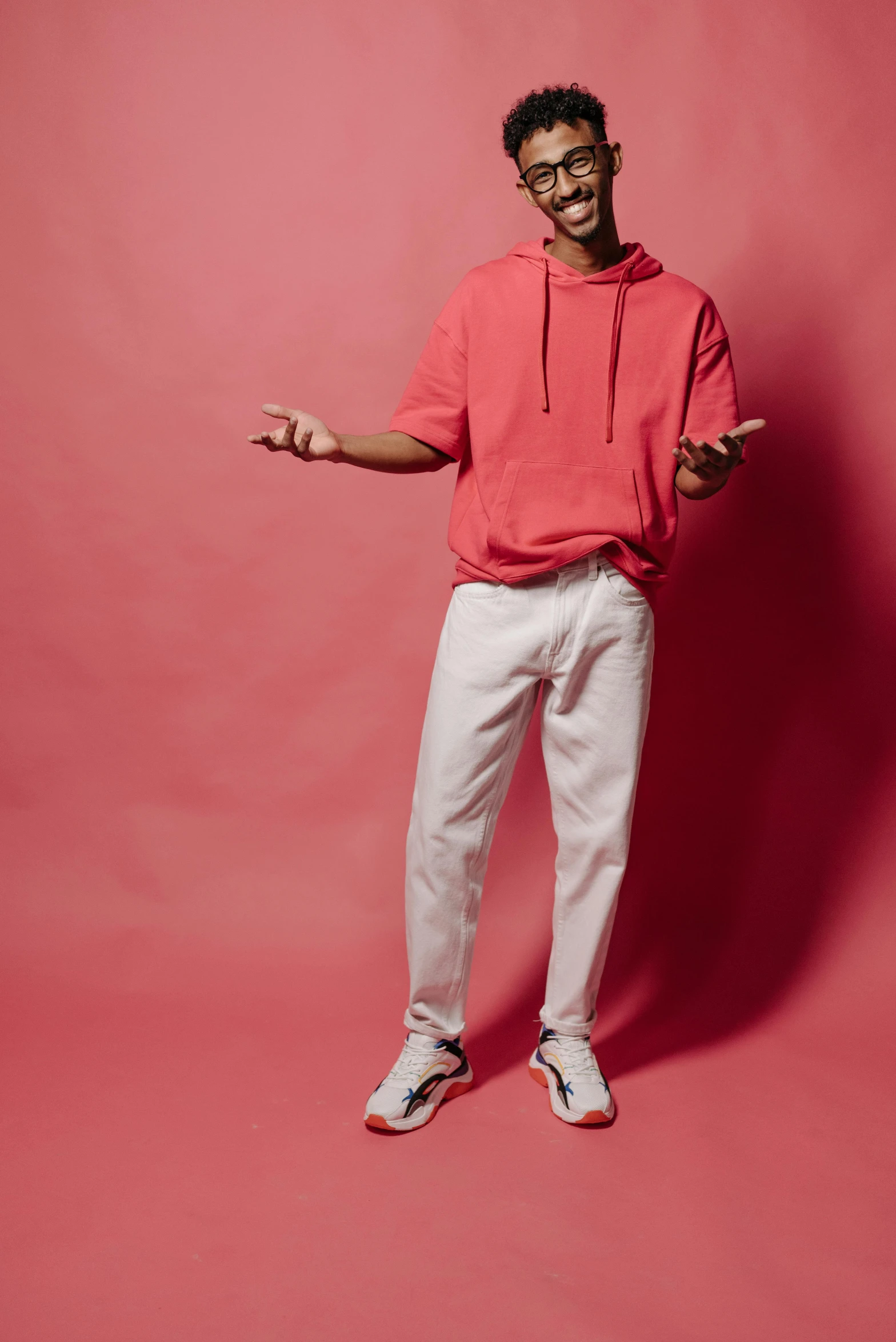 a man in a red hoodie and white pants, inspired by Louis Hersent, pexels contest winner, studio background, white and pink, jeans and t shirt, no - text no - logo