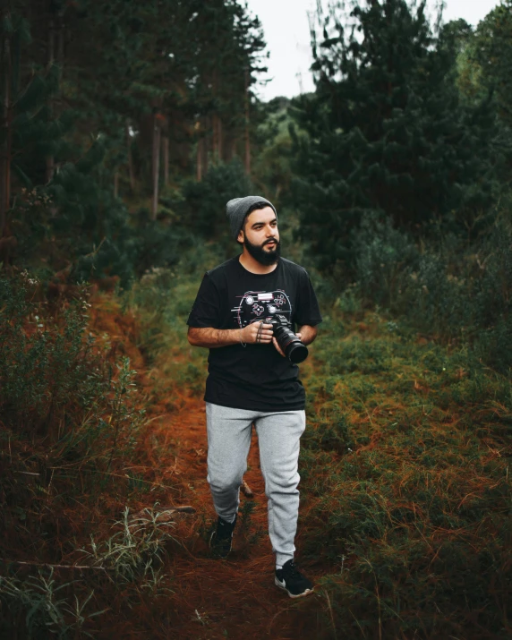 a man standing in the middle of a forest, a polaroid photo, pexels contest winner, graffiti, graphic tees, walking to the right, a portrait of rahul kohli, slightly pixelated