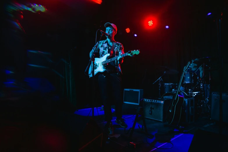 a man standing on a stage with a guitar, unsplash, private press, stage at a club, vibrantly lush, band, lachlan bailey