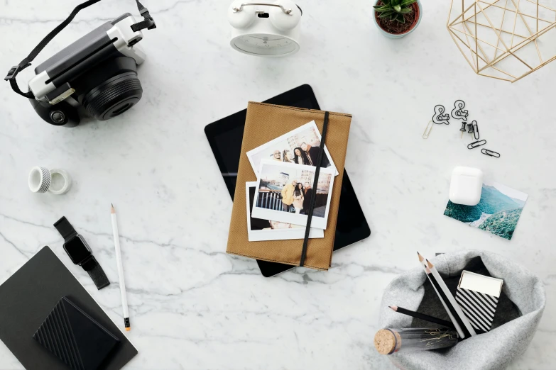 an overhead view of a desk with a camera, notebook and other office supplies, a polaroid photo, black marble and gold, 9 9 designs, photograph ”, large portrait