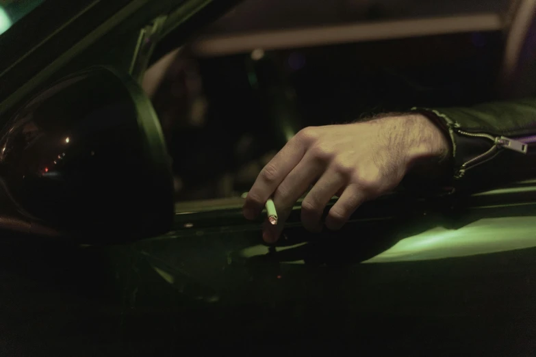 a close up of a person's hand in a car, an album cover, by Elsa Bleda, smoking a joint, night time footage, 8 k film still, green tint