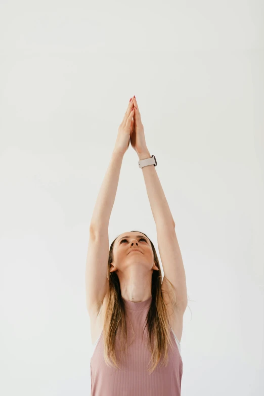 a woman standing in a yoga pose with her hands in the air, by Carey Morris, trending on unsplash, white background, extremely long forehead, kirsi salonen, low quality photo
