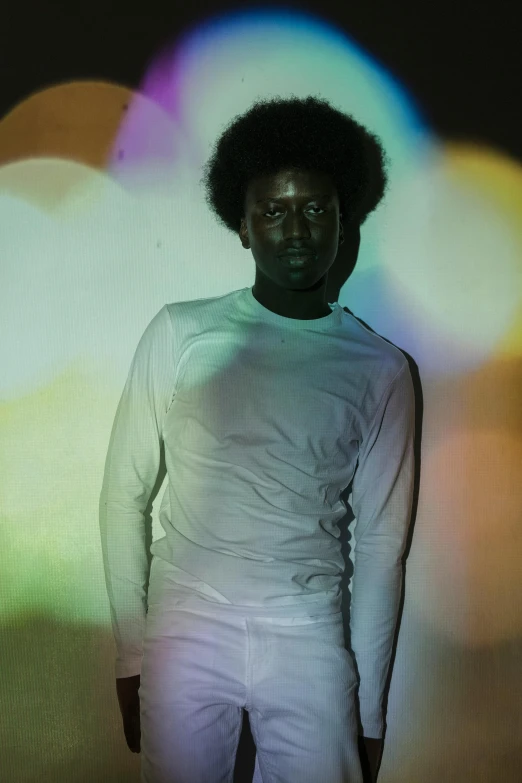 a man standing in front of a rainbow light, inspired by Barkley Hendricks, black man with afro hair, white holographic plastic, press photos, translucent