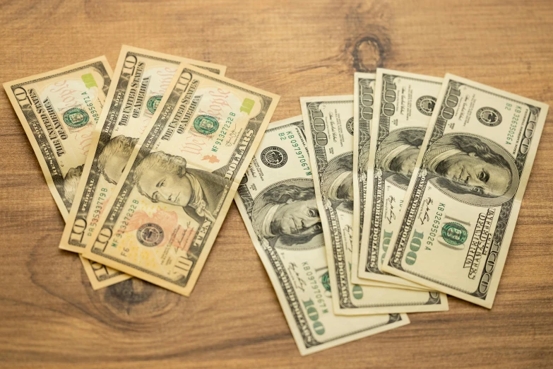 a pile of money sitting on top of a wooden table, on a table, thumbnail, featured, usa-sep 20
