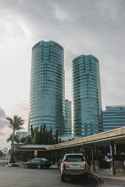 a street filled with lots of traffic next to tall buildings, reddit, bali, circular towers, aquamarine windows, viewed from the ocean