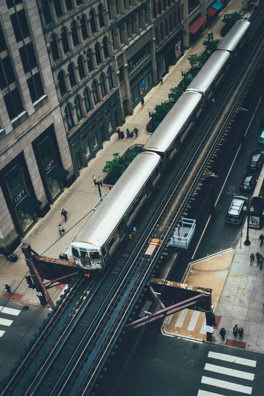 a train traveling down train tracks next to tall buildings, pexels contest winner, modern chicago streets, high view, 🚿🗝📝