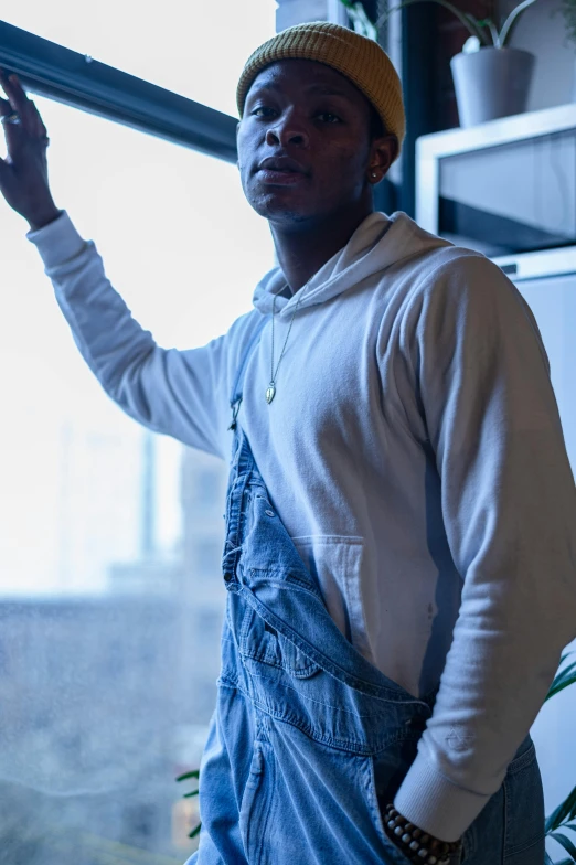 a man that is standing in front of a window, trending on pexels, kendrick lamar, wearing blue jean overalls, wearing a white sweater, profile image