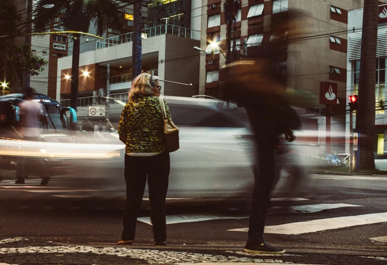 a woman waiting to cross the street at an intersection, pexels contest winner, futuristic sao paulo, early evening, older woman, instagram photo