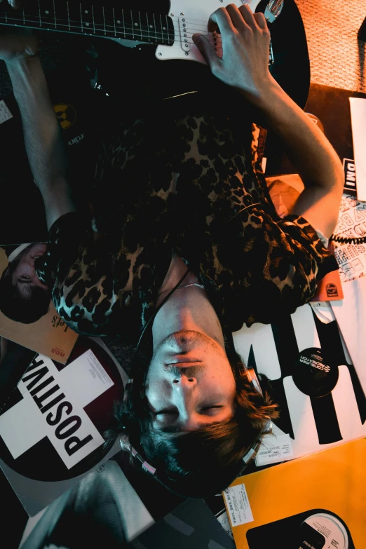 a man laying on top of a bed next to a guitar, an album cover, trending on pexels, happening, photography of charline von heyl, concert, grim fashion model looking up, high angle