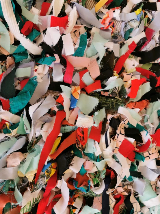 a pile of shredded paper sitting on top of a table, an album cover, inspired by John Chamberlain, unsplash, fabrics textiles, texture detail, red green black teal, areas rugs