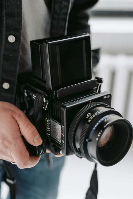 a close up of a person holding a camera, unsplash, photorealism, large format film camera, medium format. soft light, towering over the camera, mid-shot of a hunky