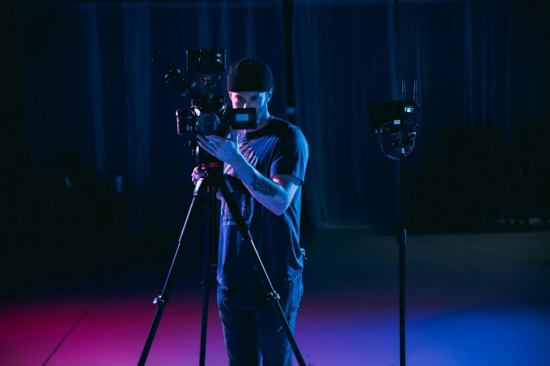 a man that is standing in front of a camera, unsplash, video art, cinematic blue lighting, digital cinema camera, purple scene lighting, production ig studios