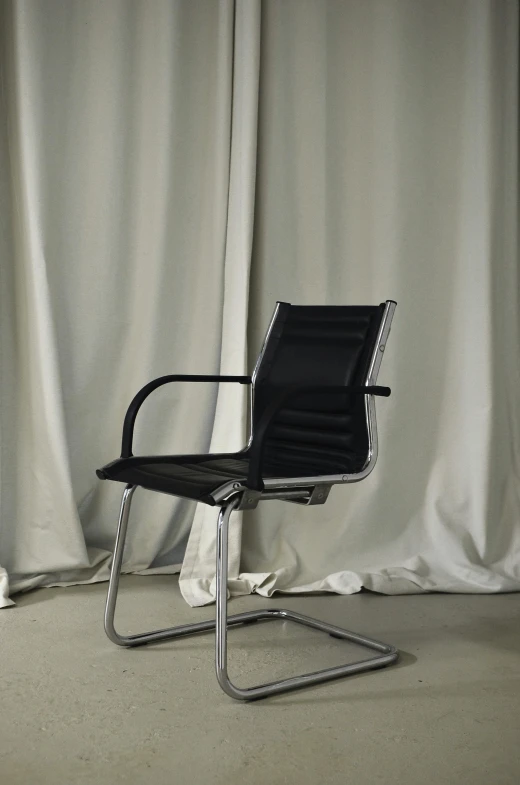 a black chair sitting in front of a white curtain, by Jens Søndergaard, sitting in office, aluminium, on black background, ergonomic