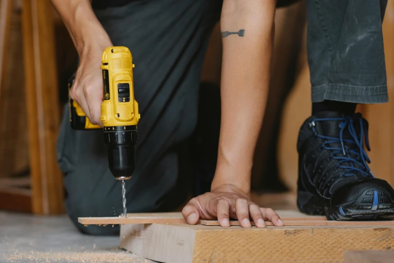 a person using a power drill on a piece of wood, pexels contest winner, yellow hardhat, 🦩🪐🐞👩🏻🦳, skilled homeless, athletic build