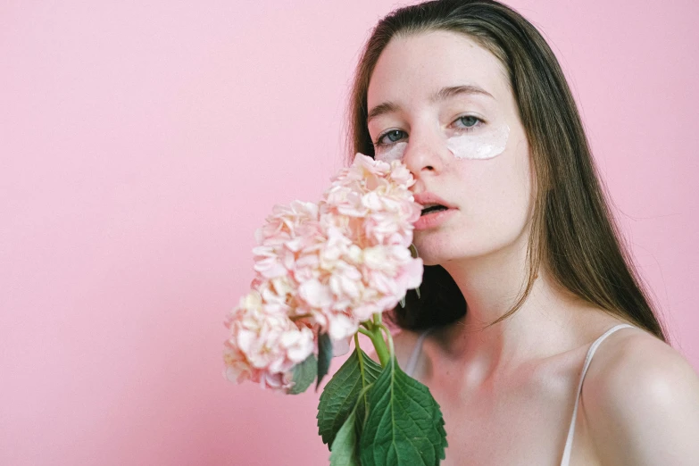 a woman holding a flower in front of her face, an album cover, trending on pexels, aestheticism, pastel pink skin tone, a plaster on her cheek, photoshoot for skincare brand, white facepaint