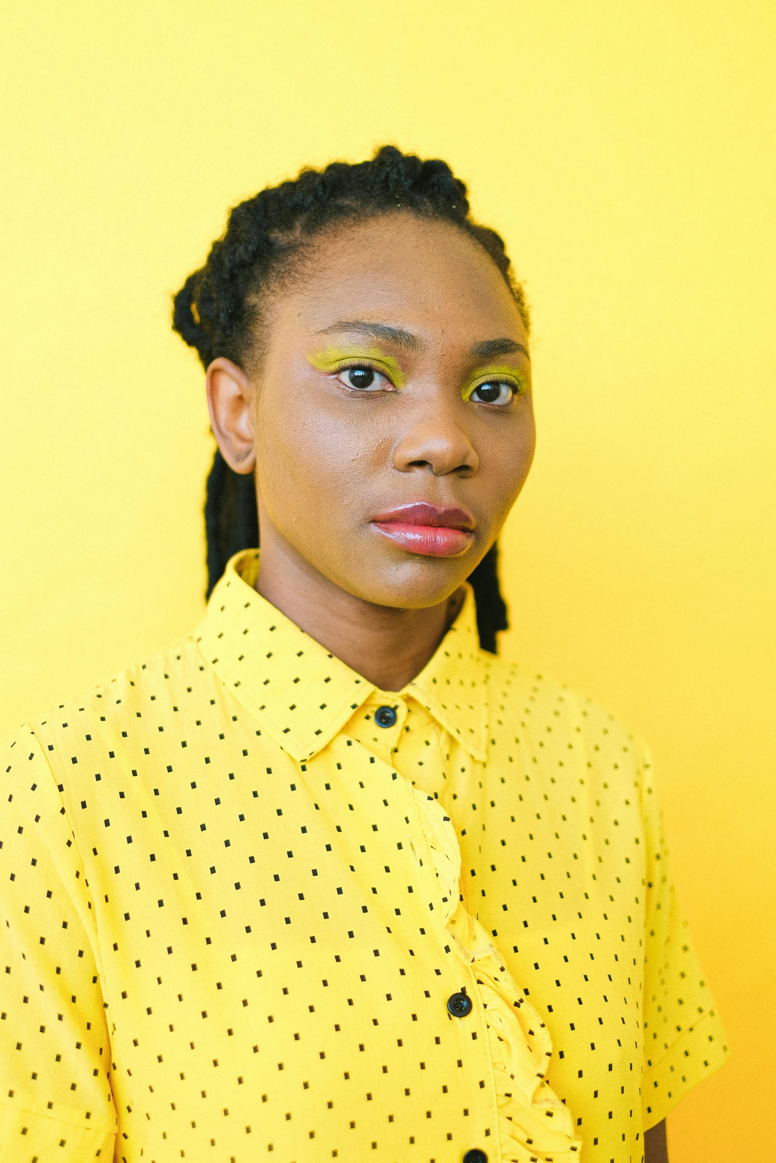 a woman standing in front of a yellow wall, trending on pexels, afrofuturism, portrait androgynous girl, 1 / 4 headshot, taken in the late 2010s, promotional image