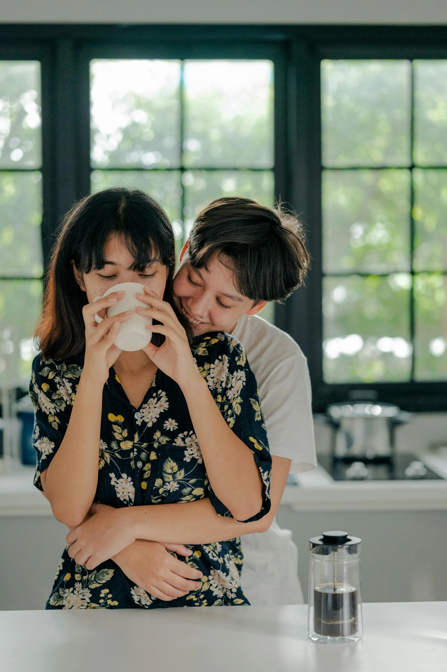 a man and woman standing next to each other in a kitchen, a picture, by Tan Ting-pho, trending on unsplash, romanticism, drinking a cup of coffee, lesbian embrace, taiwan, giggling