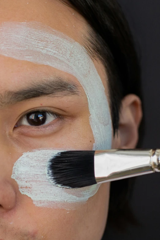 a close up of a person with paint on their face, inspired by Kanō Naizen, reddit, hyperrealism, green facemask, stipple brush technique, square masculine facial features, putting makeup on