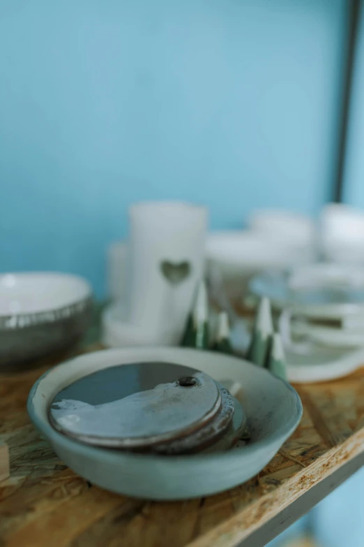 a table topped with plates and bowls on top of a wooden table, a still life, unsplash, blue gray, low quality photo, made of glazed, holiday