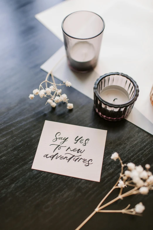 a note sitting on top of a table next to a candle, by Sara Saftleven, unsplash, joy ang, wedding, product label, multiple stories