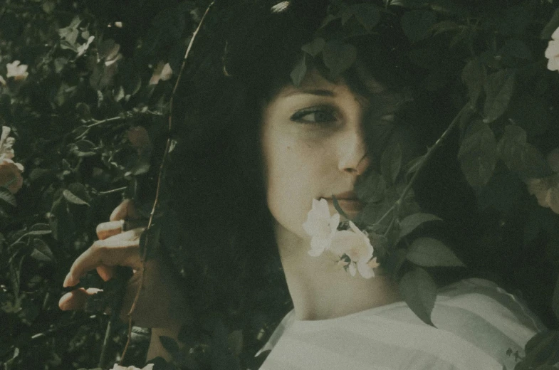 a woman with a flower in her mouth, inspired by Elsa Bleda, pexels contest winner, aestheticism, clothed in vines, vintage polaroid photo, with deep green eyes, with white skin