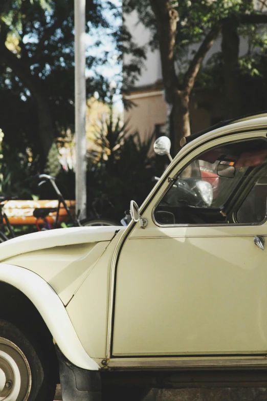 a small white car parked on the side of the road, a picture, unsplash, renaissance, yellowed with age, beetle-inspired, profile image, cars and people